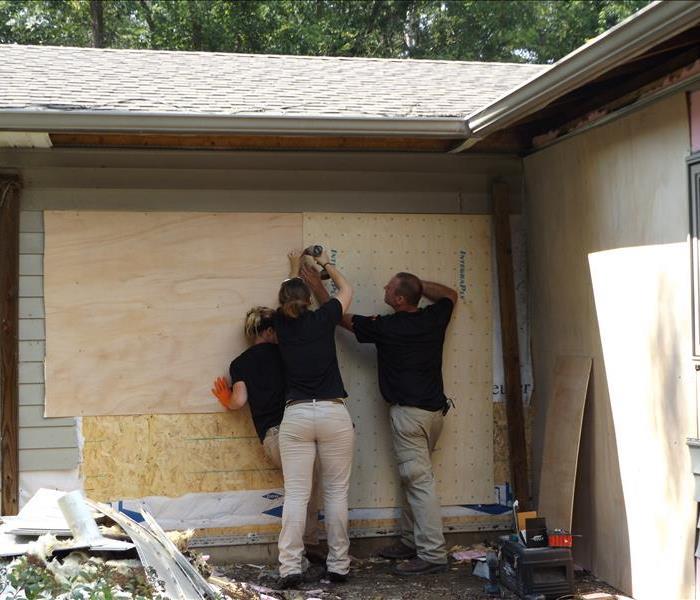 Our team members doing a board up on a storm damaged home